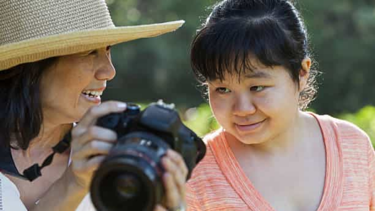 Mature Japanese woman (60s) showing photo on camera to autistic daughter (20s).